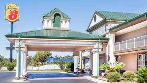 Un hotel Super 8 con techo verde, estacionamiento techado y estacionamiento cercado.