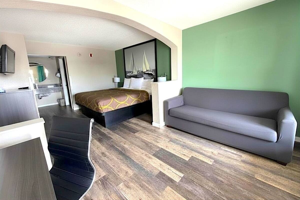 Ein Hotelzimmer mit Bett, Sofa, Schreibtisch und Fernseher.