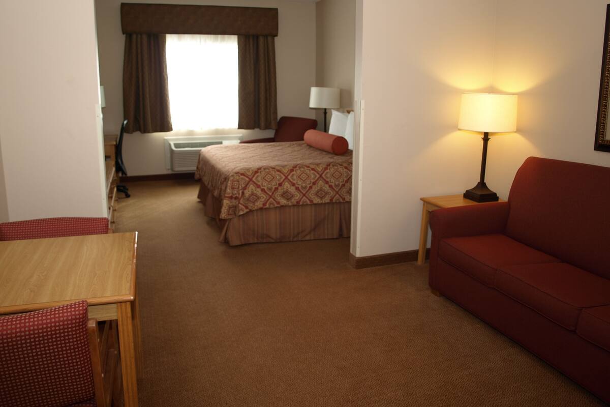 Una habitación de hotel con cama, sofá, mesa y lámpara.