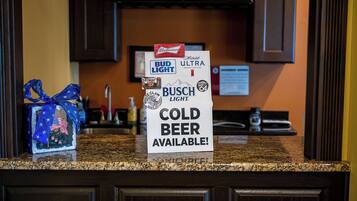 Een aanrecht met een bord waarop staat dat er koude bier beschikbaar is, waaronder merken zoals Bud Light en Busch Light.