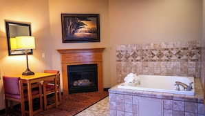 A bathroom with a tiled shower, a fireplace, a table with chairs, and a framed picture on the wall. - Savanna Inn & Suites (Savanna)