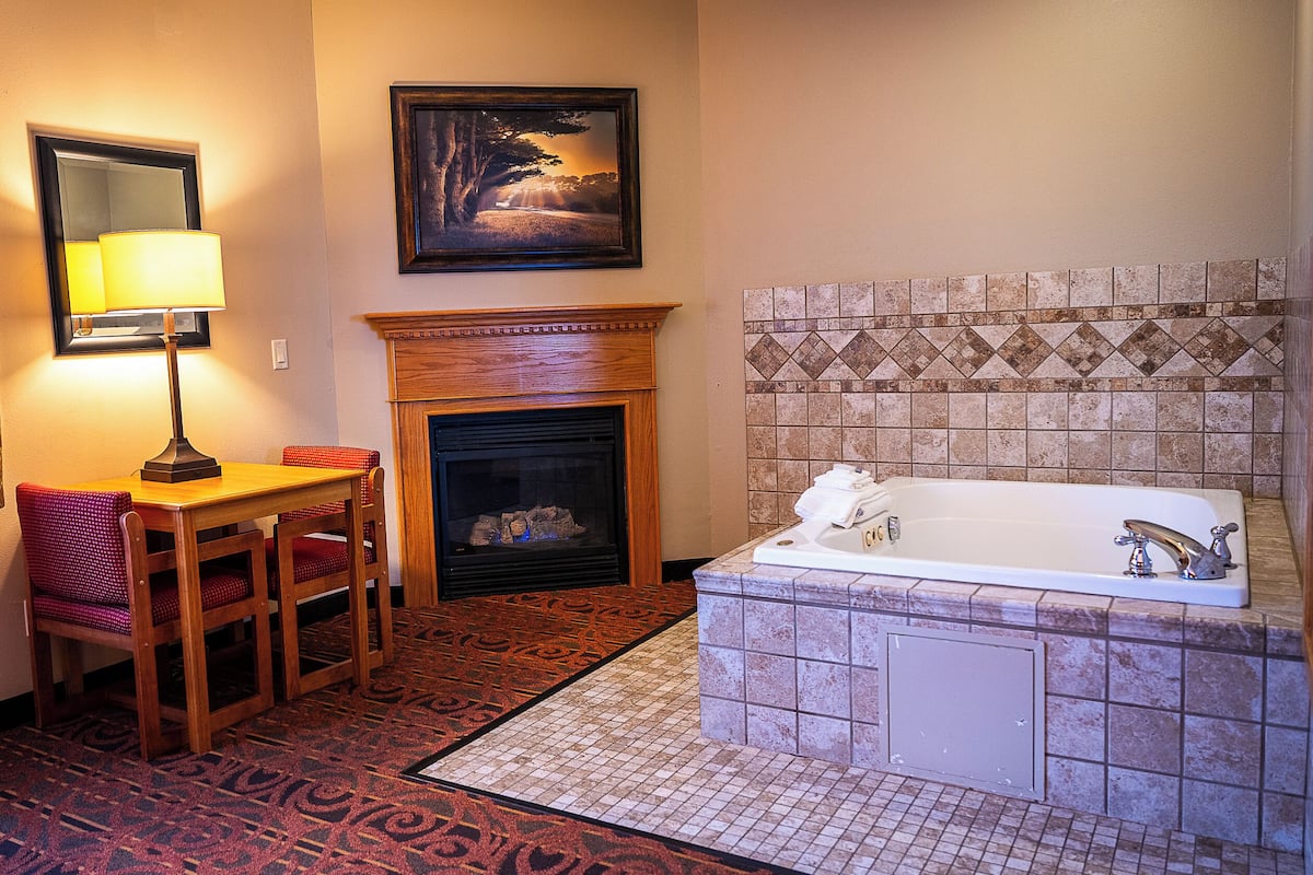 Un baño con ducha de azulejos, chimenea, mesa con sillas e imagen enmarcadas en la pared.