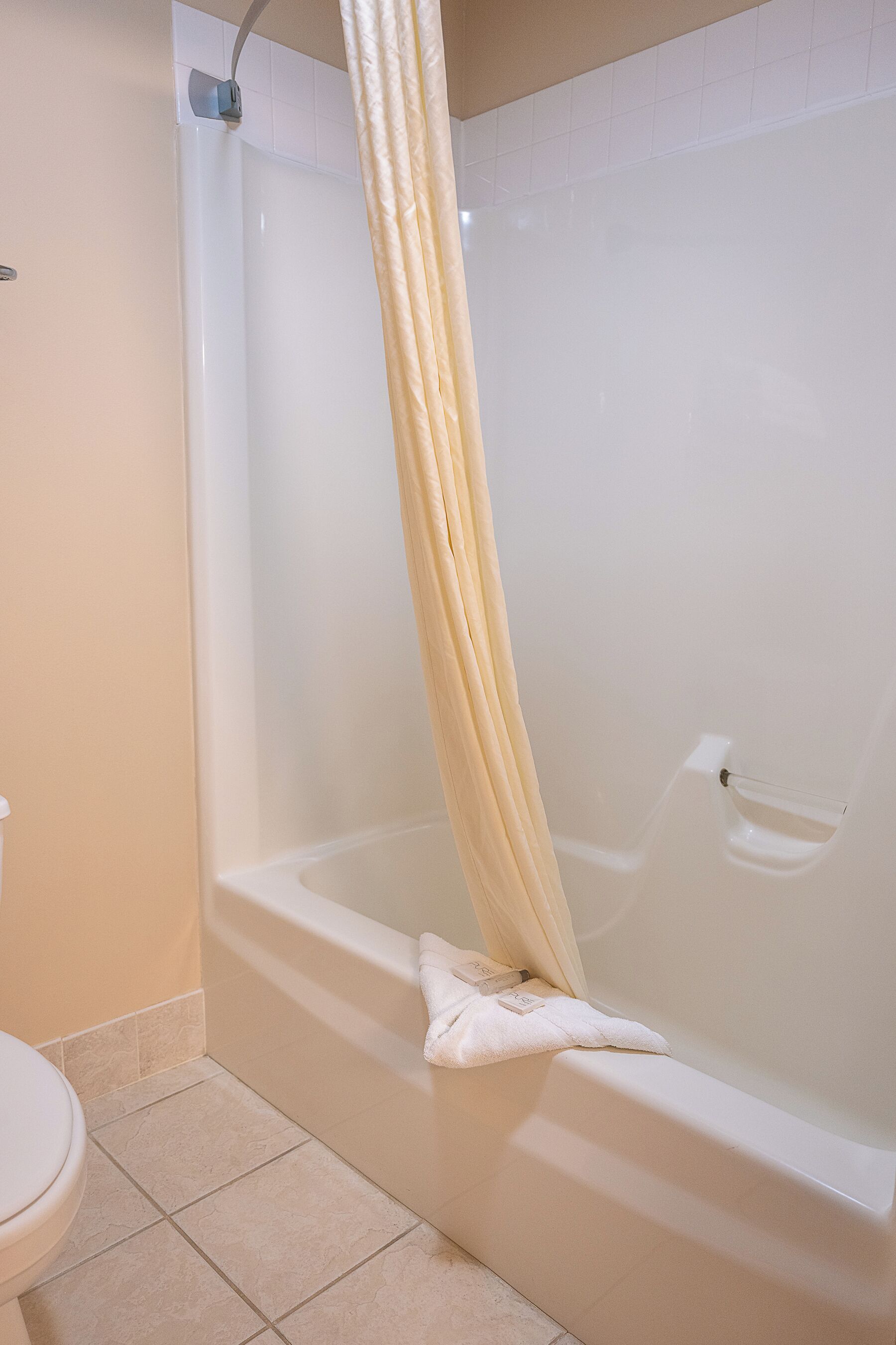 A bathroom with a bathtub, a toilet, and a shower curtain.
