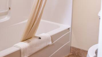 A bathroom with a bathtub, a shower curtain, and a toilet.