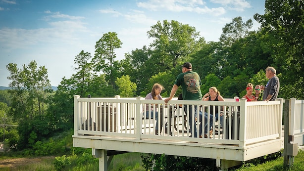 A deck with a railing overlooking a grassy area with trees. - Savanna Inn & Suites (Savanna)