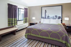 A hotel room with a bed, bench, air conditioning unit, two bedside tables with lamps, and a cityscape painting on the wall. - Super 8 by Wyndham Chicago/Rosemont/O'Hare/SE (River Grove)
