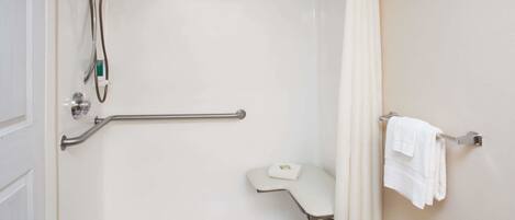 A shower area with a grab bar, a towel rack, and a small bench.