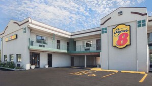 A Super 8 hotel with a two-story structure, a balcony on the upper level, and a parking lot with handicapped parking spaces. - Super 8 by Wyndham Chicago/Rosemont/O'Hare/SE (River Grove)