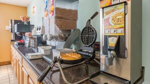 Una zona de cocina con una plancha para gofres, una máquina de café y un dispensador de gofres.