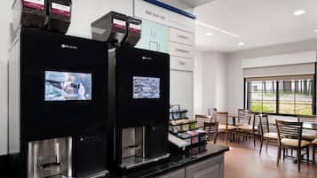 A coffee station with two coffee dispensers, a screen displaying coffee-related content, and a menu board above.