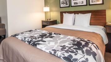 A hotel room with a bed, a nightstand with a lamp, and framed pictures on the wall.