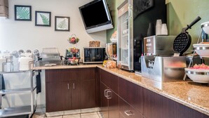Une cuisine moderne équipée d’un four à micro-ondes, d’un grille-pain, d’un appareil à gaufres et de divers autres appareils électroménagers.