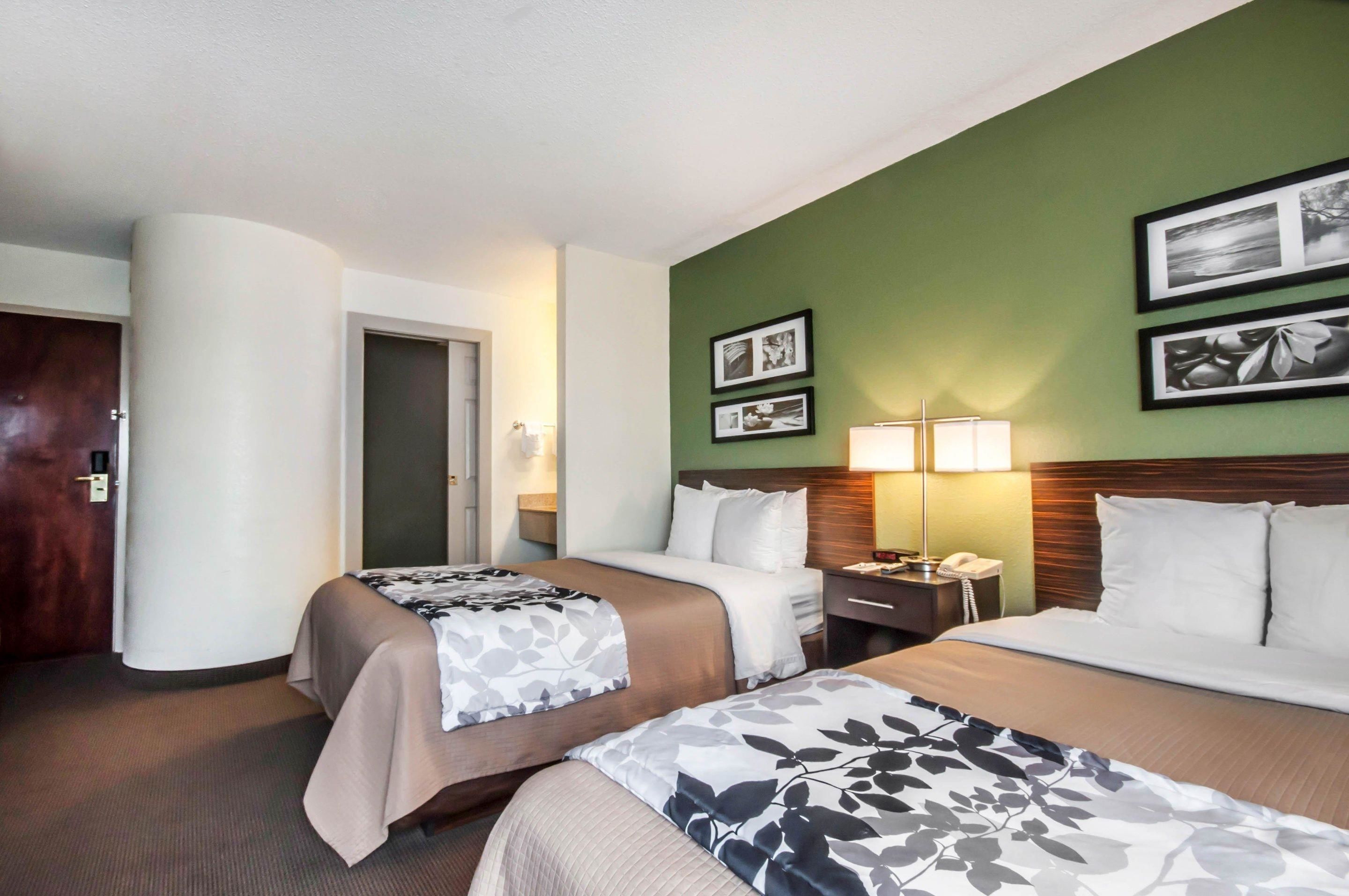 Una habitación de hotel con dos camas, una mesita de noche con lámpara y cuadros en la pared.