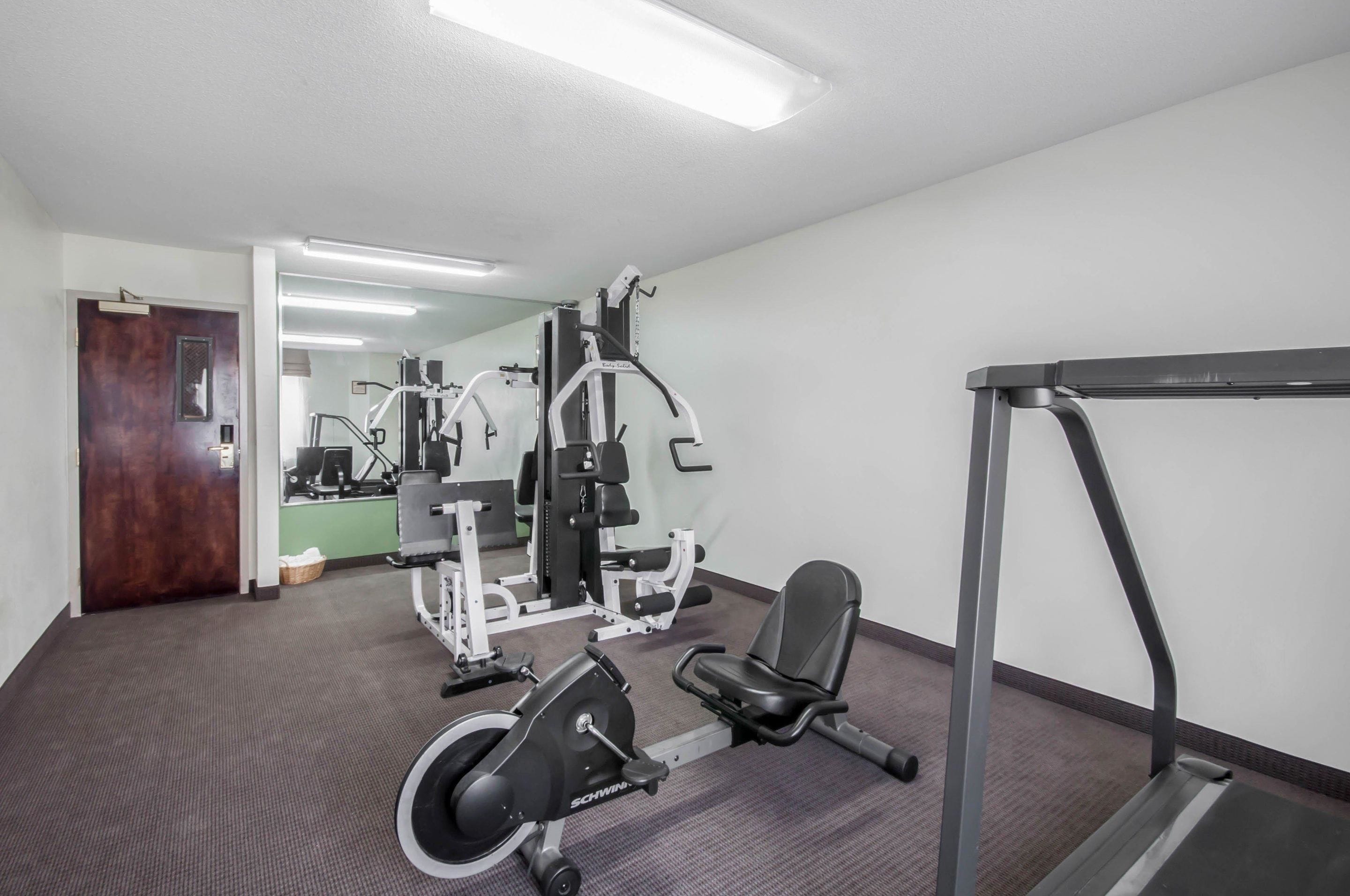 A gym with cardio equipment, a mirror, and a treadmill.