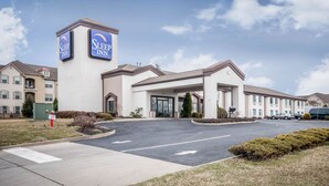 Un hôtel Sleep Inn doté d’une entrée principale, d’un parking et offrant une vue sur un ciel dégagé.