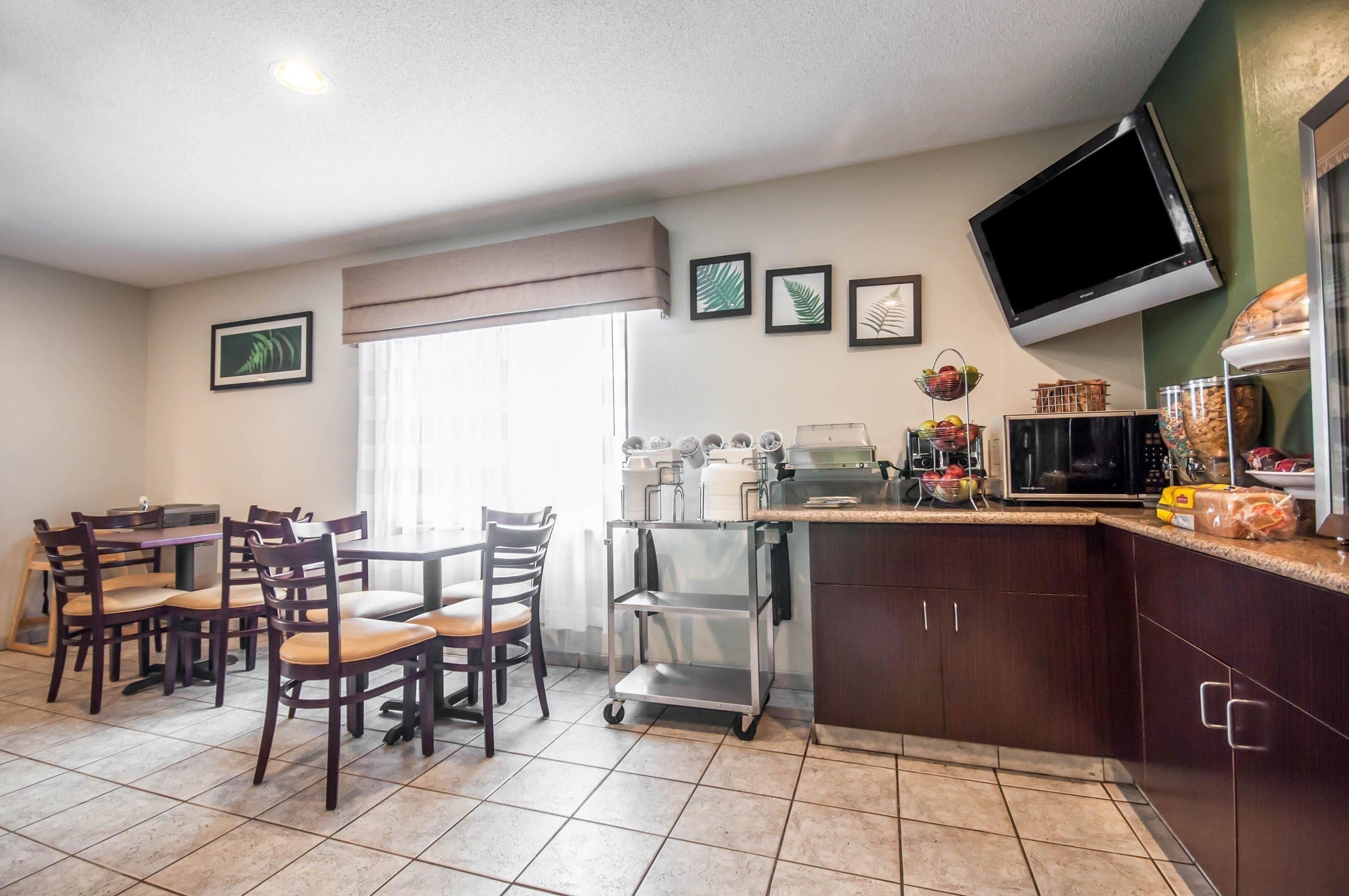 A kitchen with a dining area, equipped with a coffee machine, a microwave, and a TV mounted on the wall.