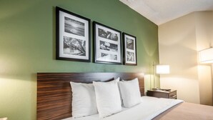 Une chambre d’hôtel avec un grand lit, une tête de lit en bois et trois photographies encadrées accrochées au mur.