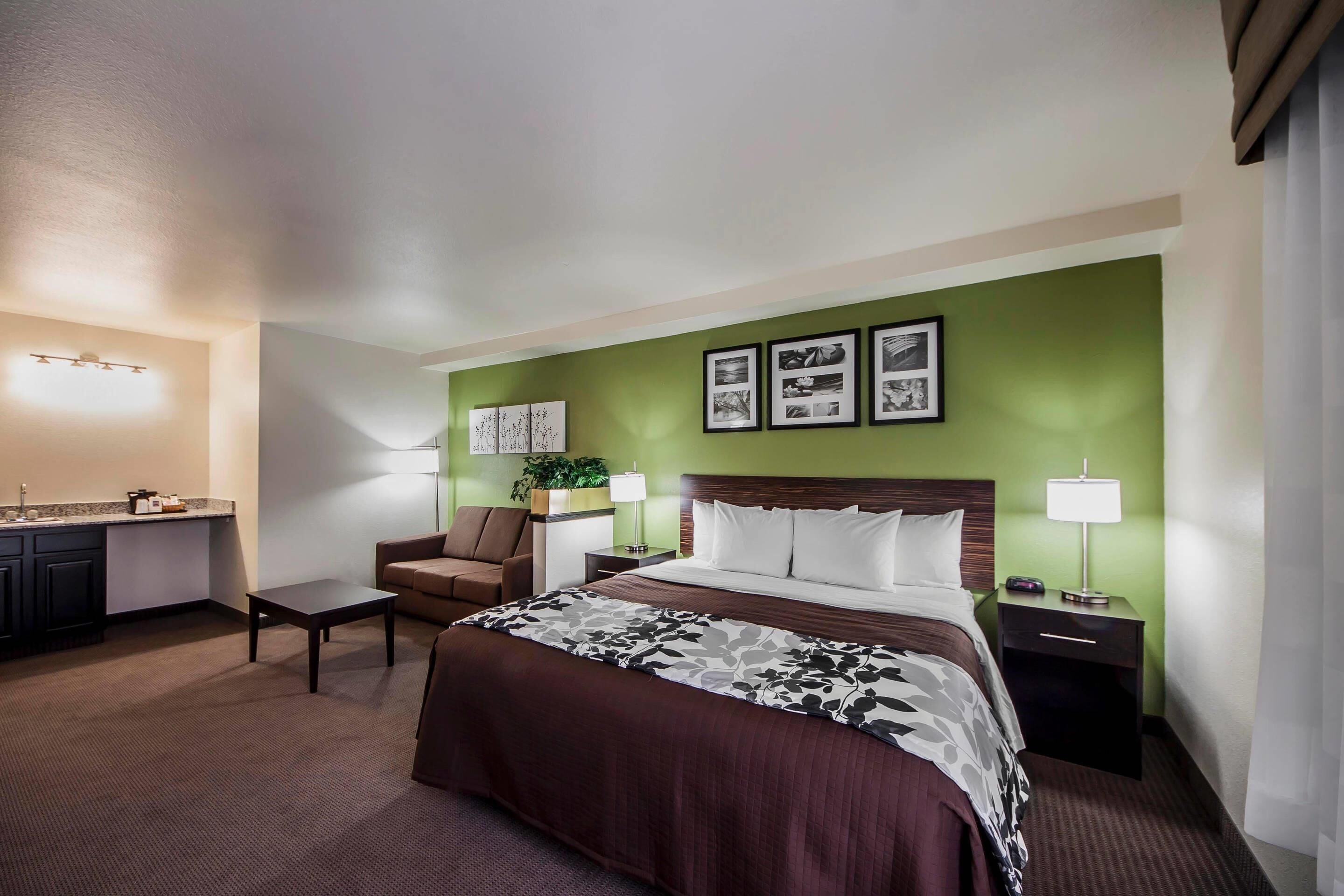 Hotelkamer met een bed, een bureau met stoel, nachtkastje en een wandlamp.