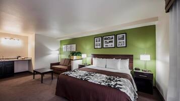 Hotelkamer met een bed, een bureau met stoel, nachtkastje en een wandlamp.