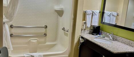 A bathroom with a bathtub, a wheelchair-accessible shower chair, a sink, and a toilet.