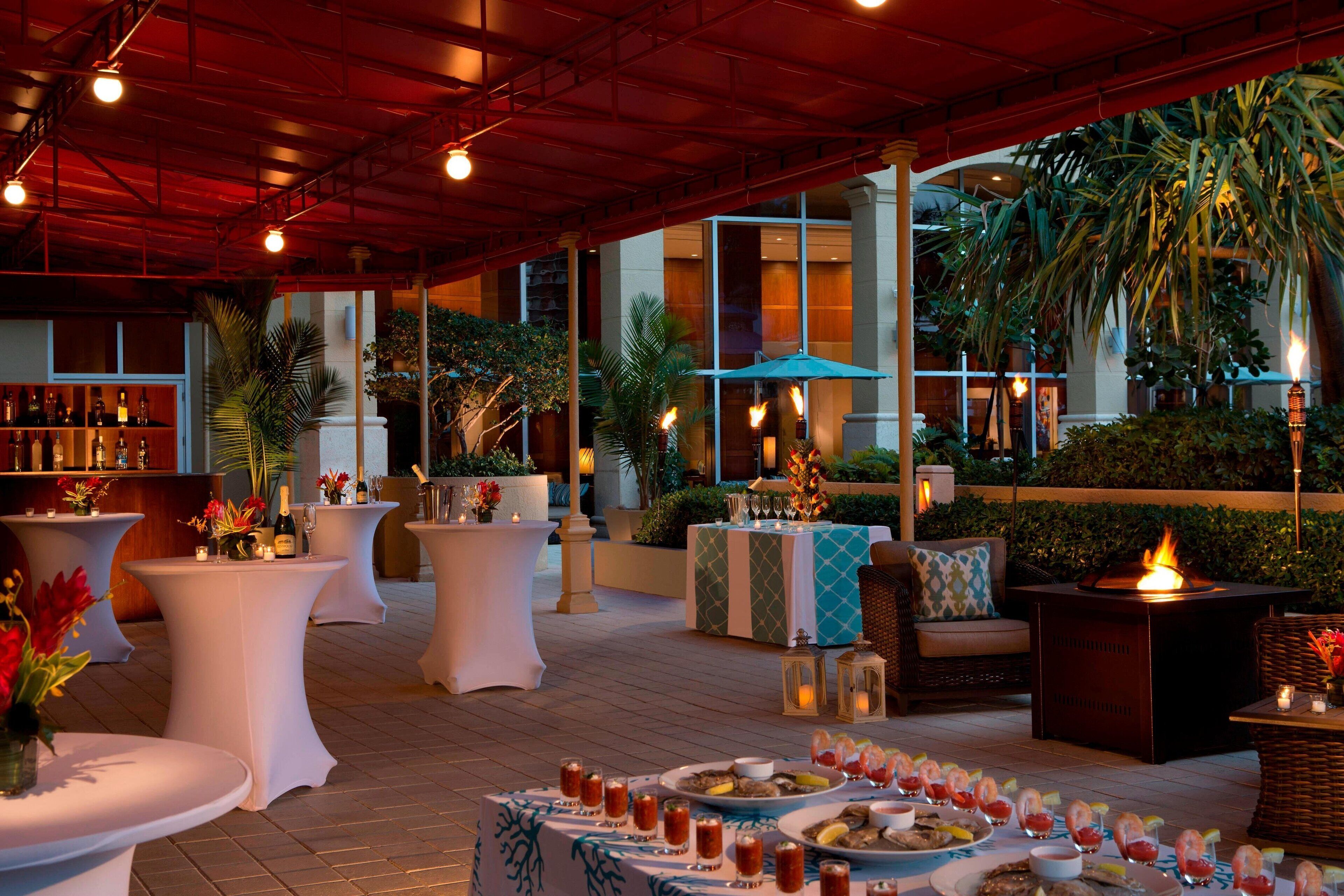 An outdoor dining area with round tables, a bar, and a fire feature.