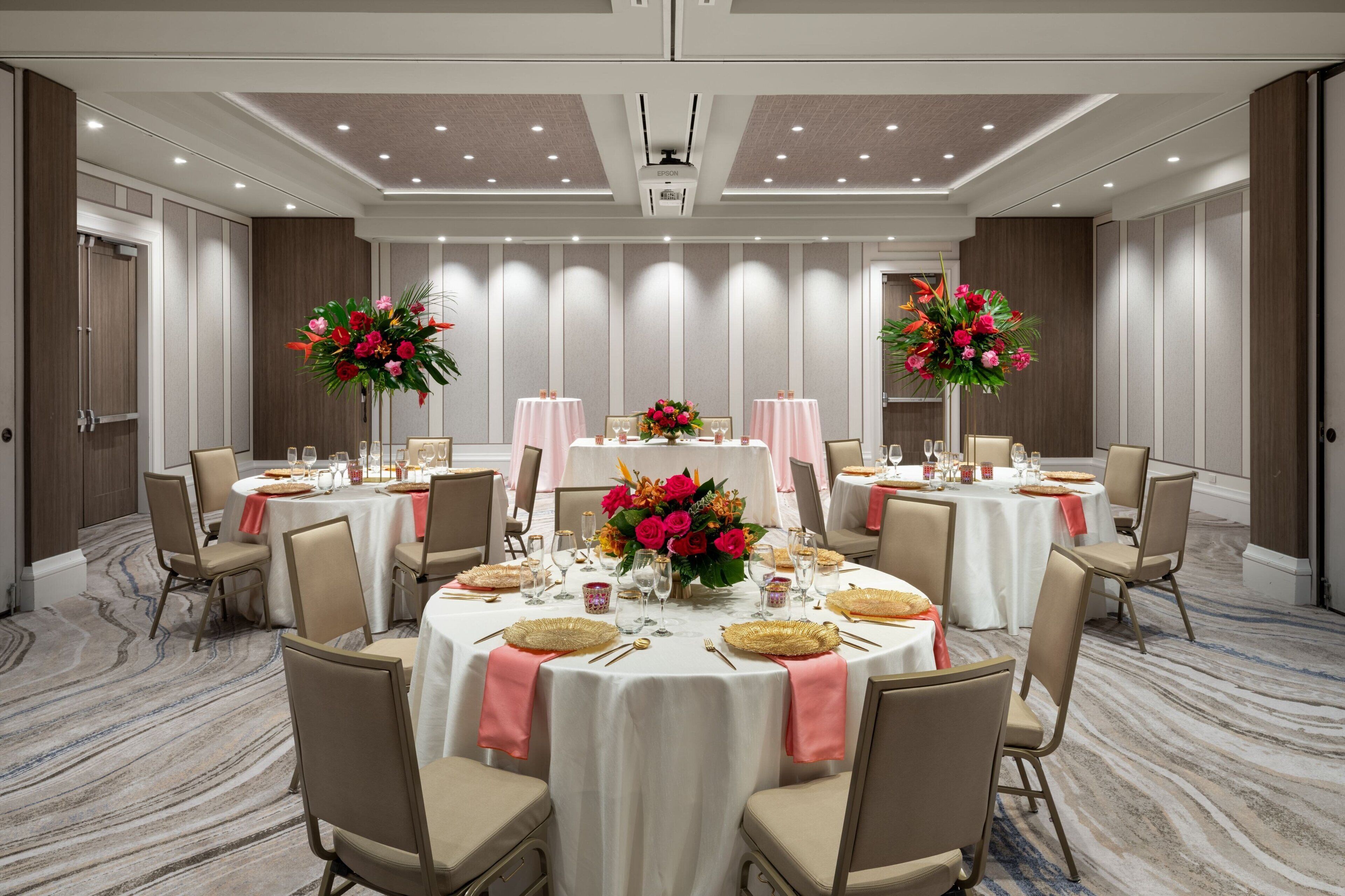 A conference room with round tables, chairs, and floral centerpieces.