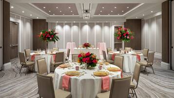A conference room with round tables, chairs, and floral centerpieces.