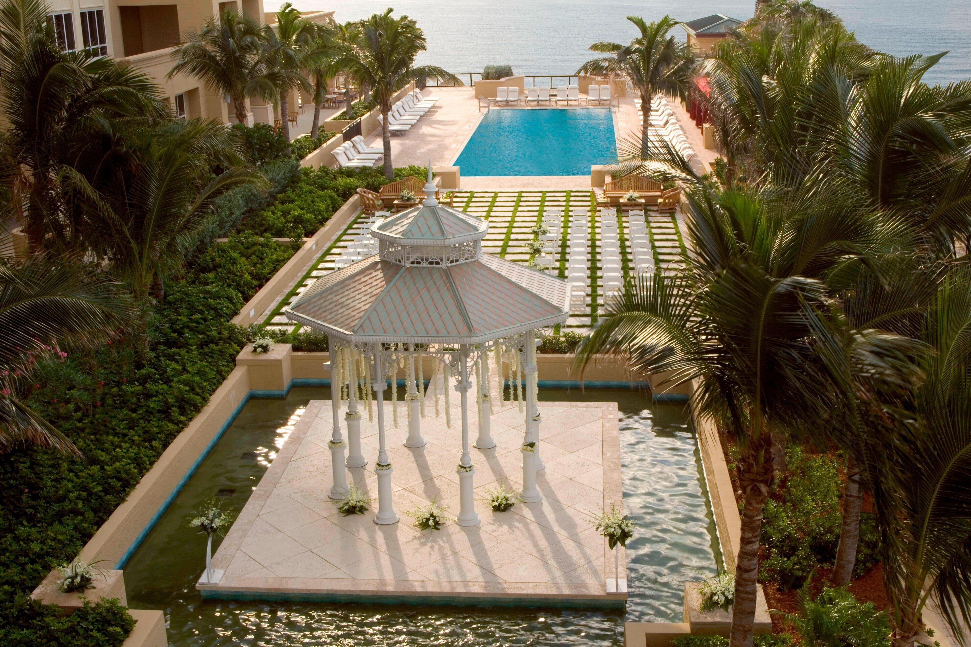 A resort with a central pool, palm trees, and a gazebo.