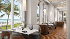 Un restaurant avec vue sur la plage, de grandes fenêtres et un décor intérieur moderne.