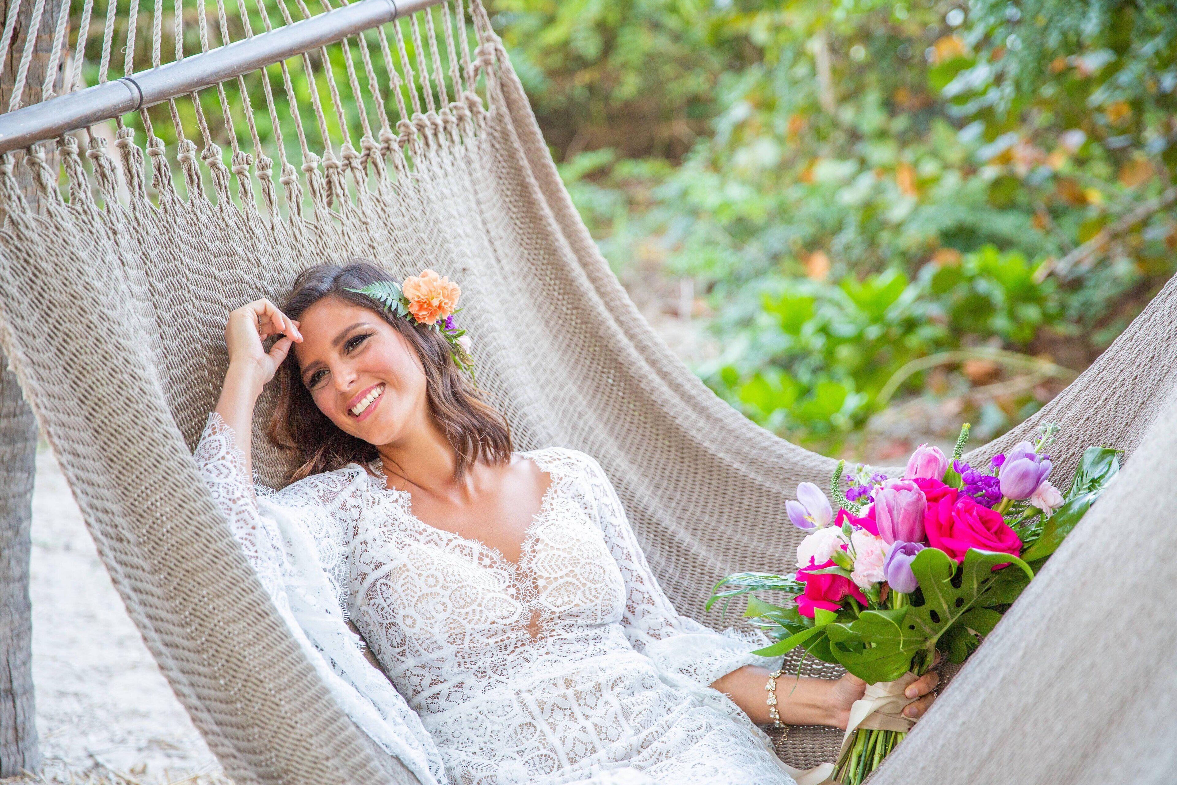 A person in a hammock chair holding a bouquet of flowers.
