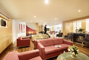 Eine moderne Hotelhalle mit einem roten Sofa, beigen Couches und einem Kamin.