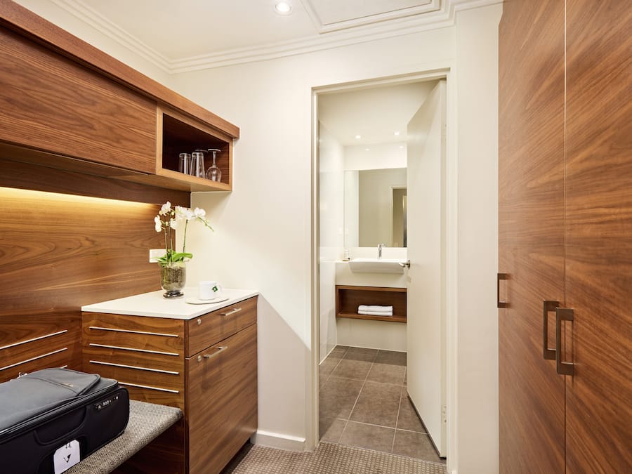 Un baño moderno con tocador de madera, un espejo y zona de ducha.