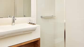 A modern bathroom with a glass-enclosed shower, a white sink with a wooden shelf, and a large mirror.
