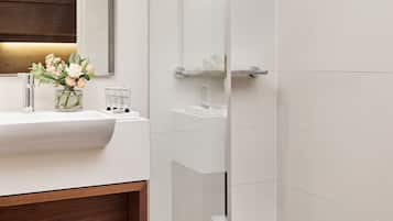 Un bagno moderno con box doccia in vetro, un lavandino bianco con ripiano in legno e uno specchio sopra al lavandino.