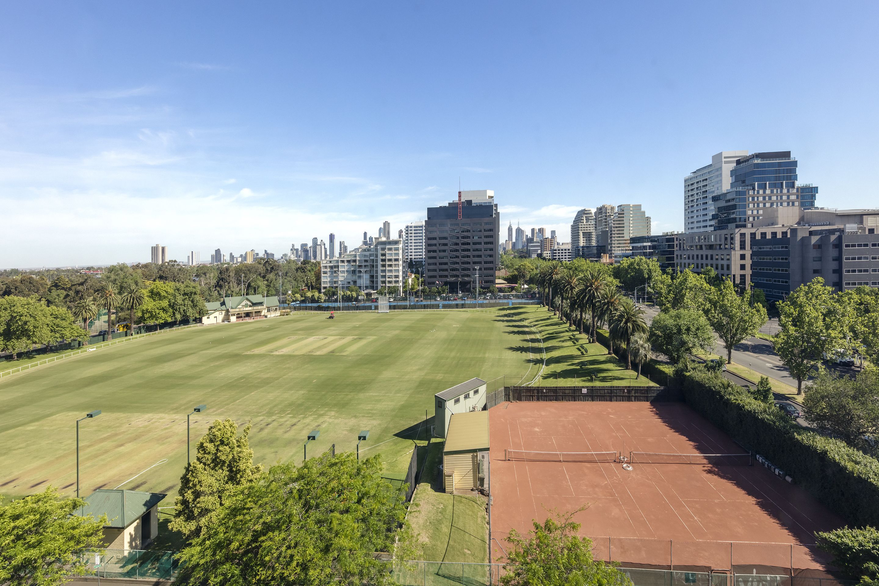 Una cancha de tenis con un horizonte urbano de fondo.