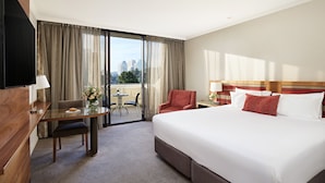 A hotel room with a large bed, a desk with a chair, a small table, and a TV. - View Melbourne (Melbourne)