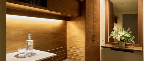 A modern bathroom with wooden cabinetry, a vanity with a mirror, and a small bench.