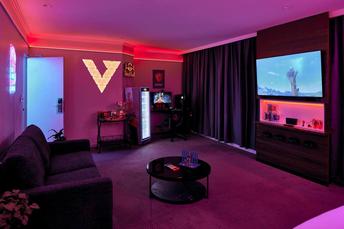 A modern living room with a large flat-screen TV, a gaming setup, and a cozy seating area.
