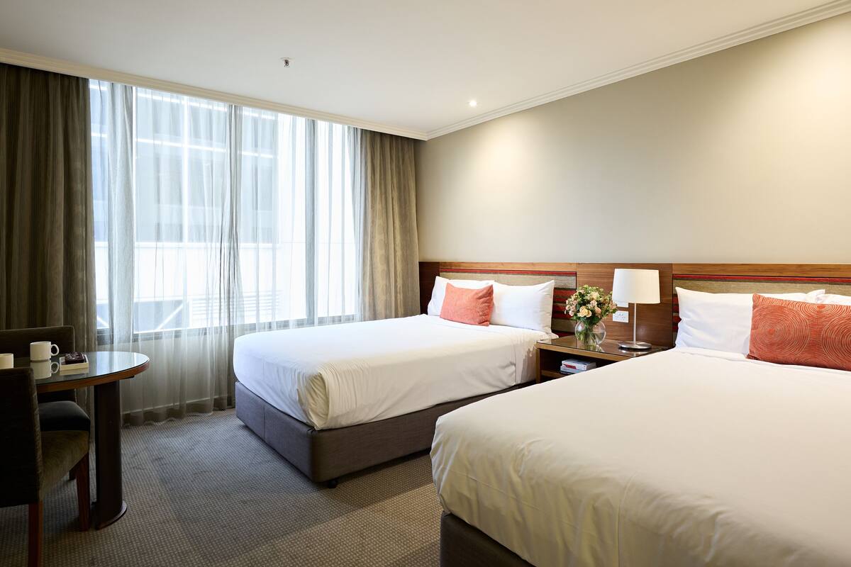 A hotel room with two beds, a desk, and a chair.