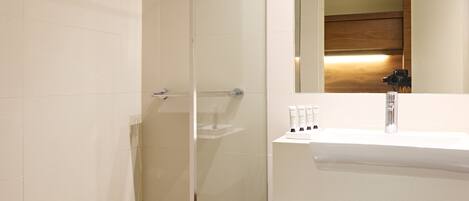 A modern bathroom with a glass-enclosed shower, a white sink with a wooden shelf, and a mirror above the sink.