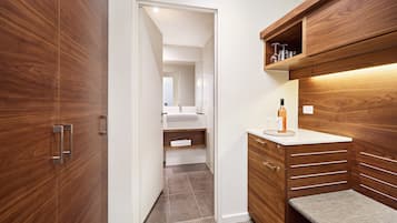 A modern bathroom with a wooden vanity, a mirror, and a shelf with toiletries.
