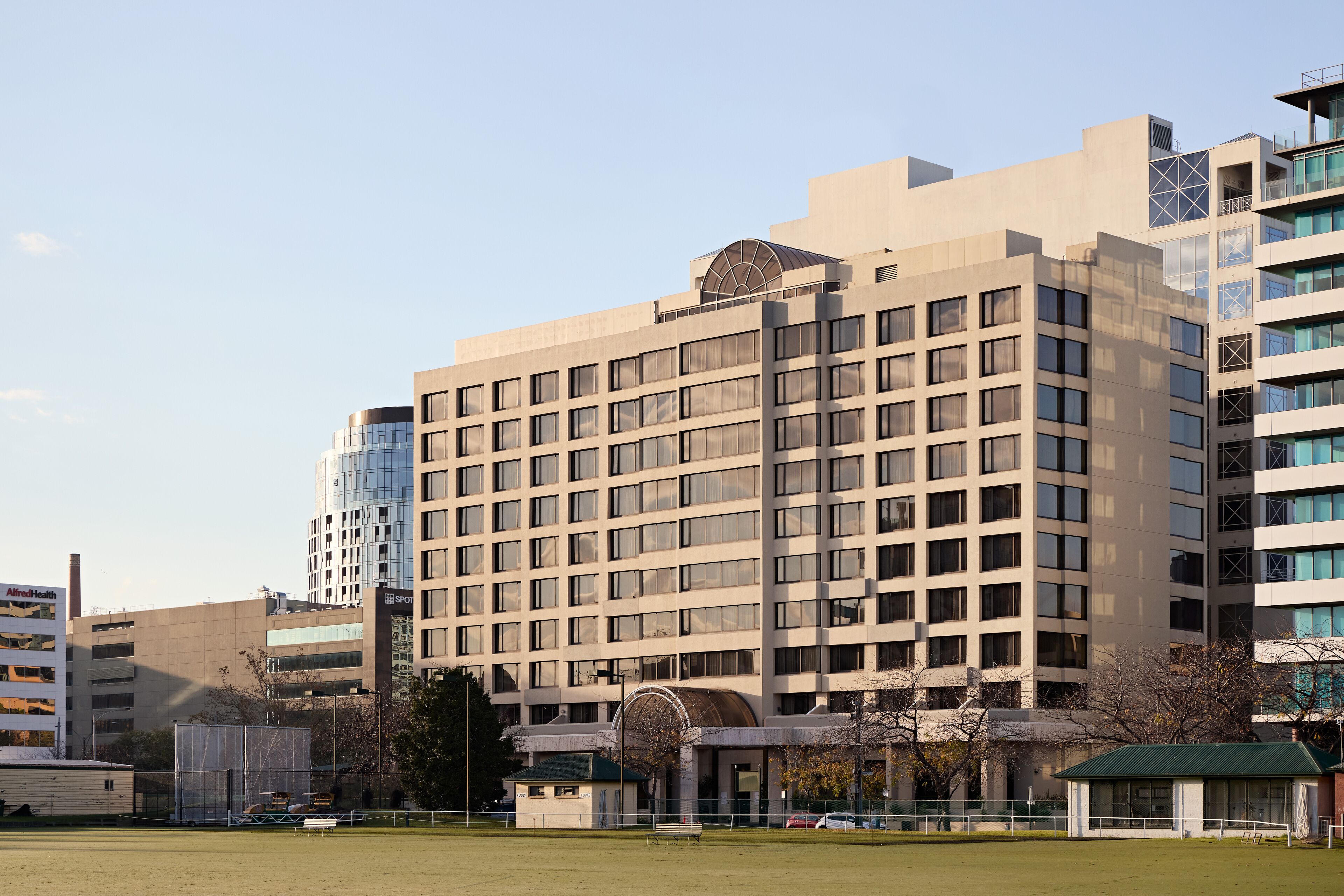 Un hotel de varios pisos con un diseño arquitectónico moderno, que cuenta con una entrada en arco destacada y un amplio patio central.