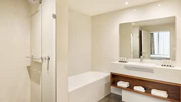 A modern bathroom with a glass-enclosed shower, a freestanding bathtub, and a vanity with a mirror and shelves for toiletries.