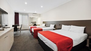 Habitación de hotel con tres camas, un escritorio y una silla.