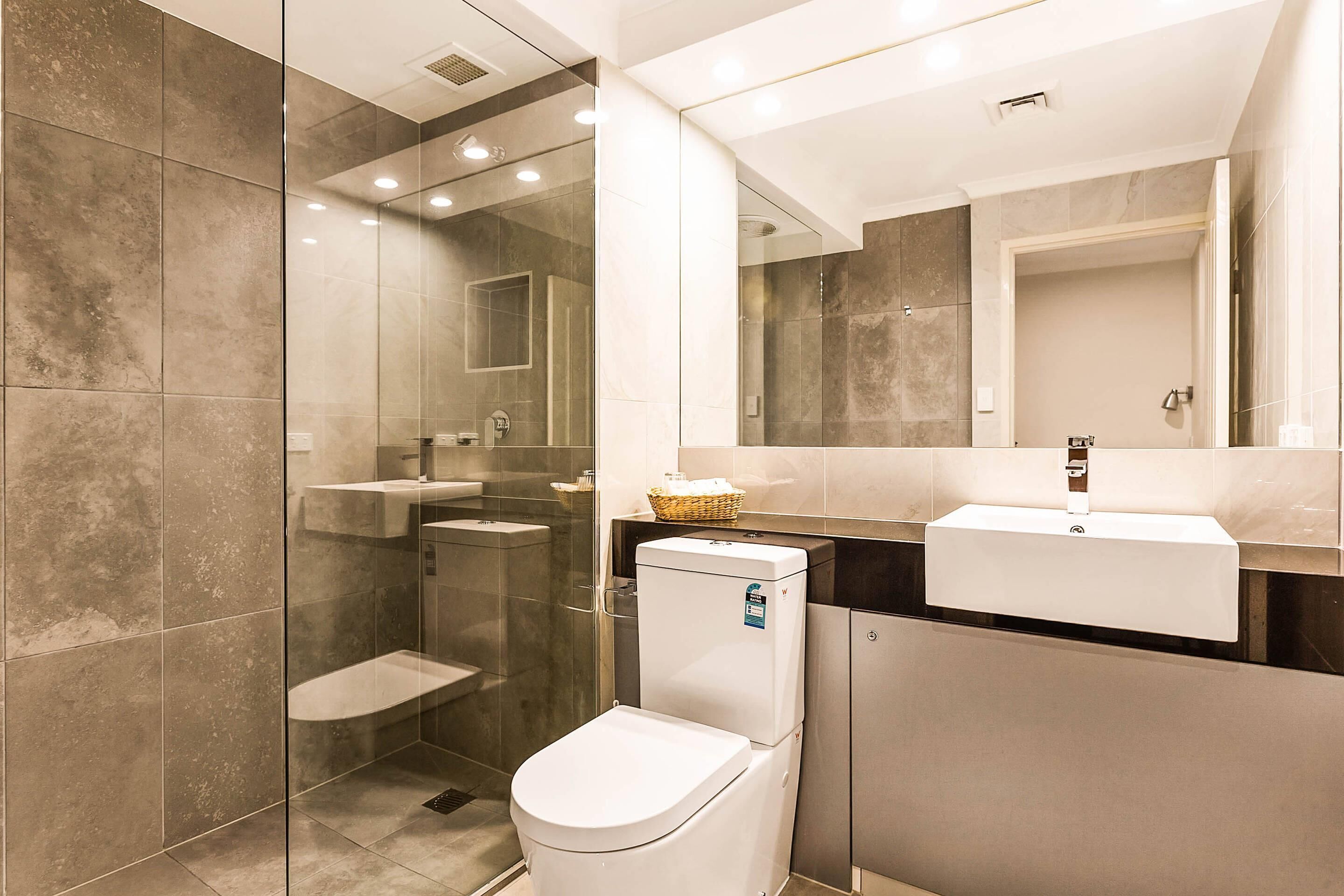 A modern bathroom with a glass-enclosed shower, a white toilet, a sink, and a mirror above the sink.