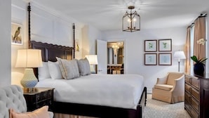 A bedroom with a bed, a chair, a dresser, and a lamp. - Deer Path Inn (Lake Forest)