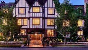 A Tudor-style hotel with a prominent entrance, multiple windows, and a well-lit facade. - Deer Path Inn (Lake Forest)