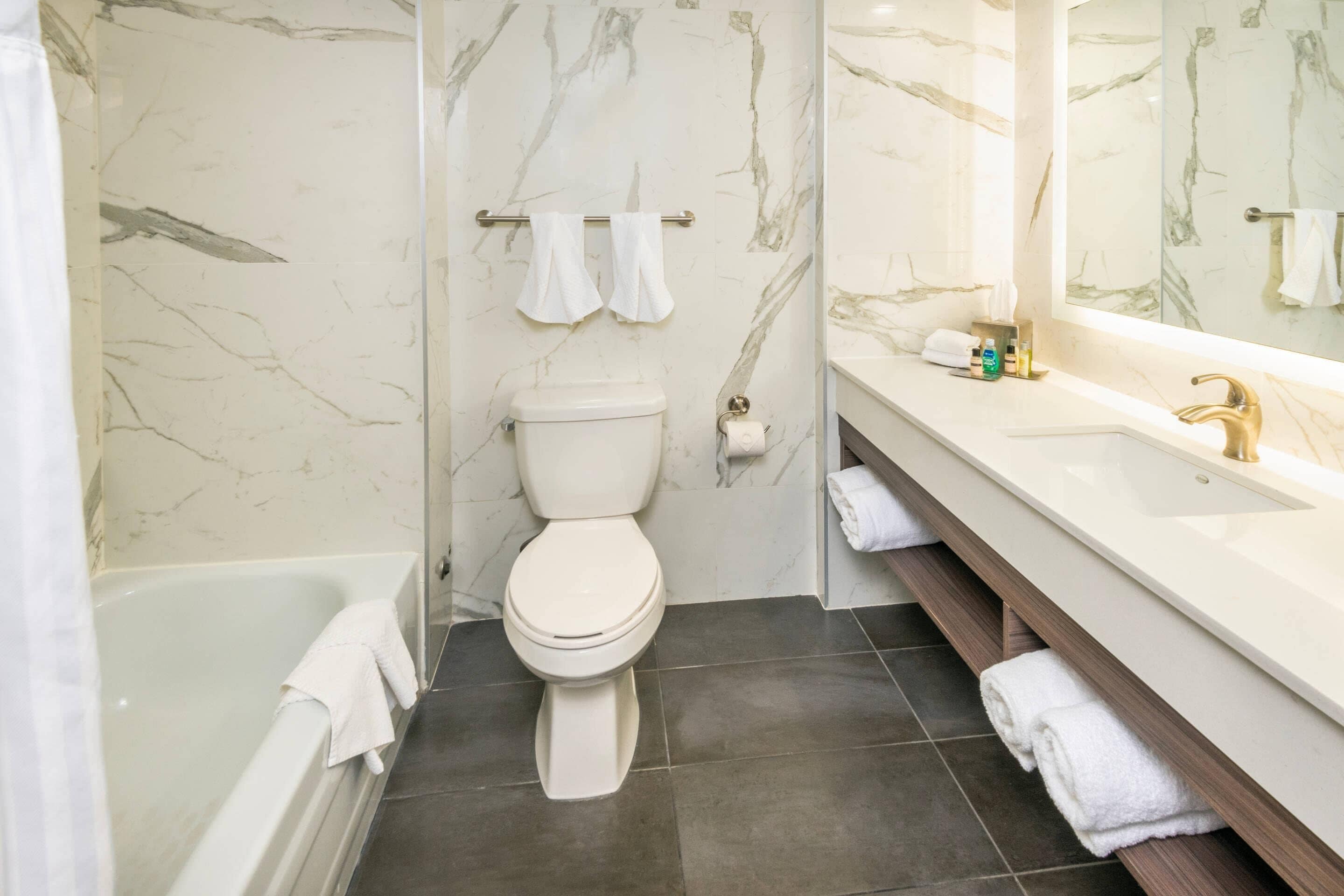 A bathroom with a bathtub, toilet, and vanity with a mirror.