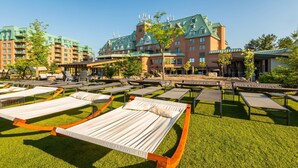 A hotel courtyard with outdoor lounge chairs and a building with green roofs in the background. - Chateau Cartier Hotel & Resort, an Ascend Collection Resort (Gatineau)