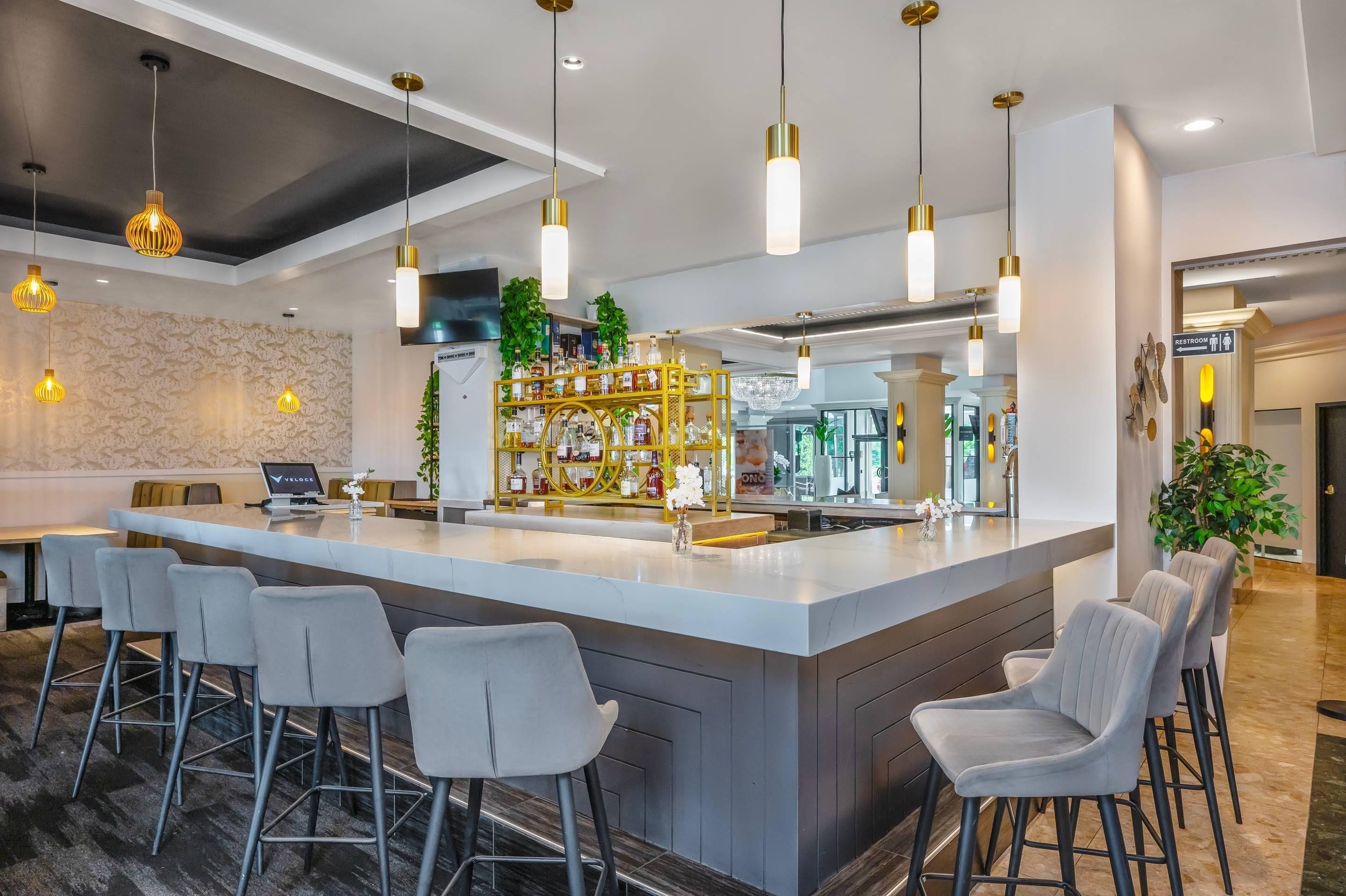 A modern bar area with a central island, bar stools, and hanging pendant lights.